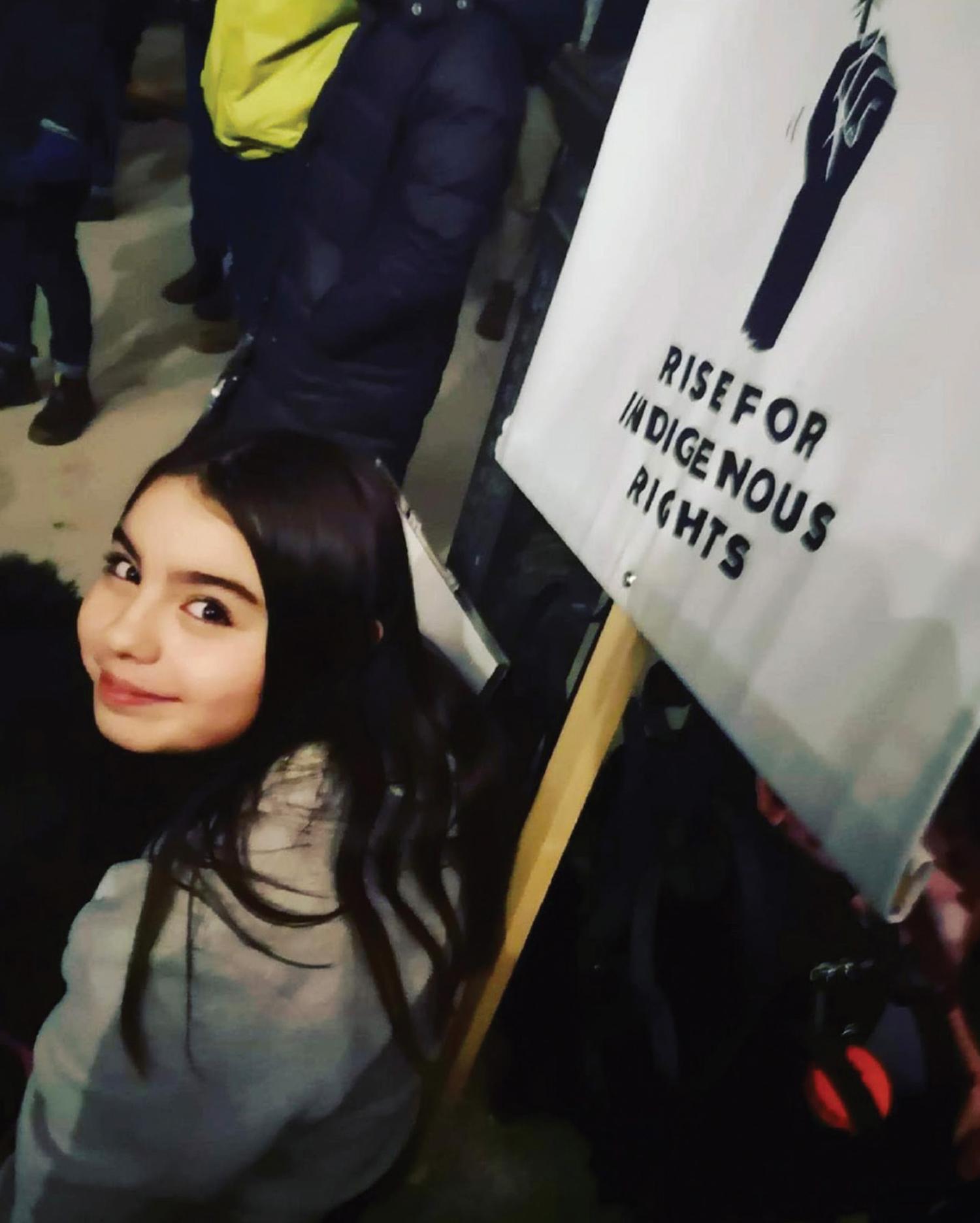 Photograph of young girl holding a rise for indigenous rights sign.