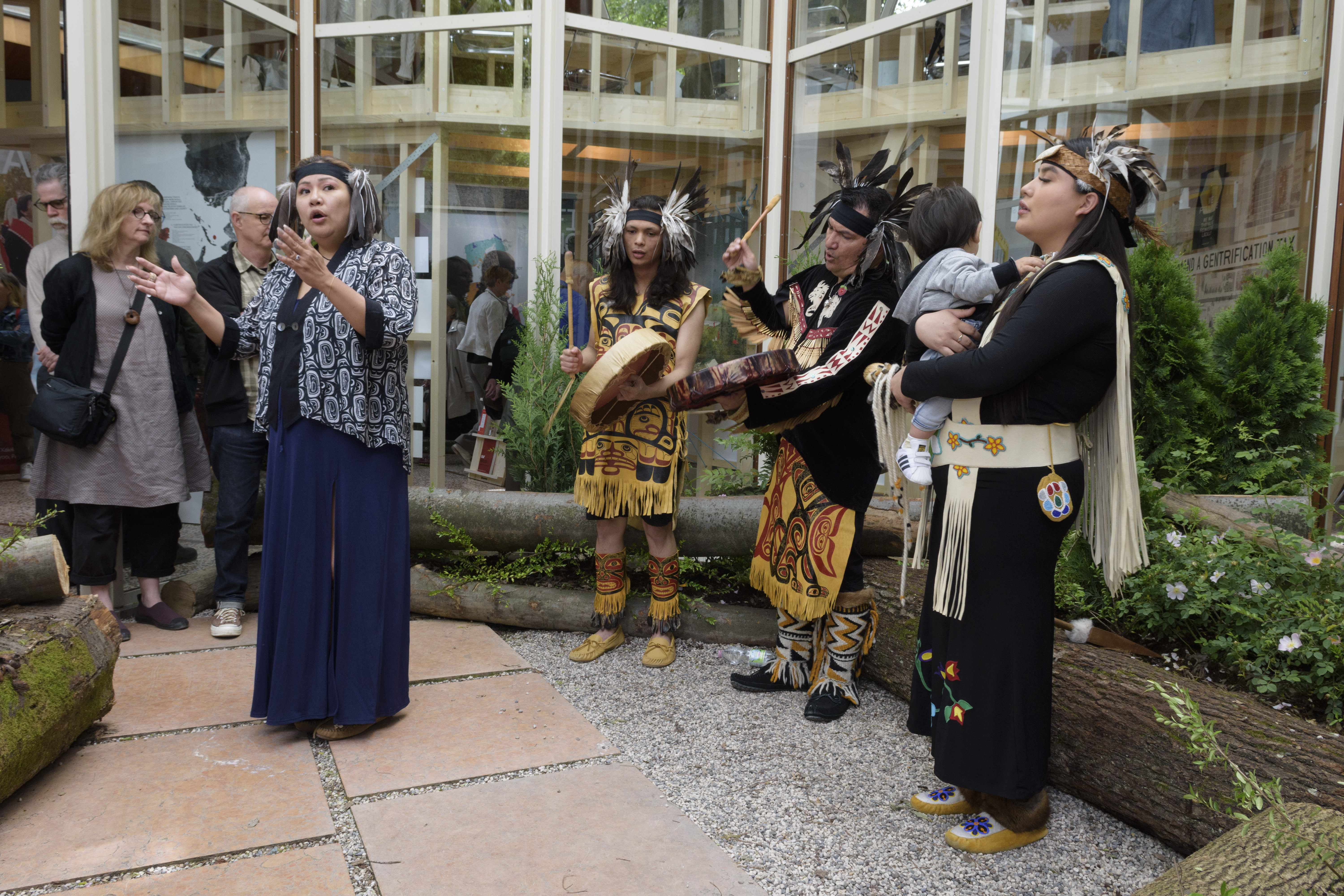Image of four singers, two of which are drumming, in the courtyard of the Canada pavilion.