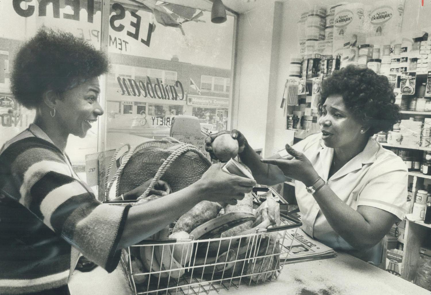 Photograph of two women speaking across a counter.